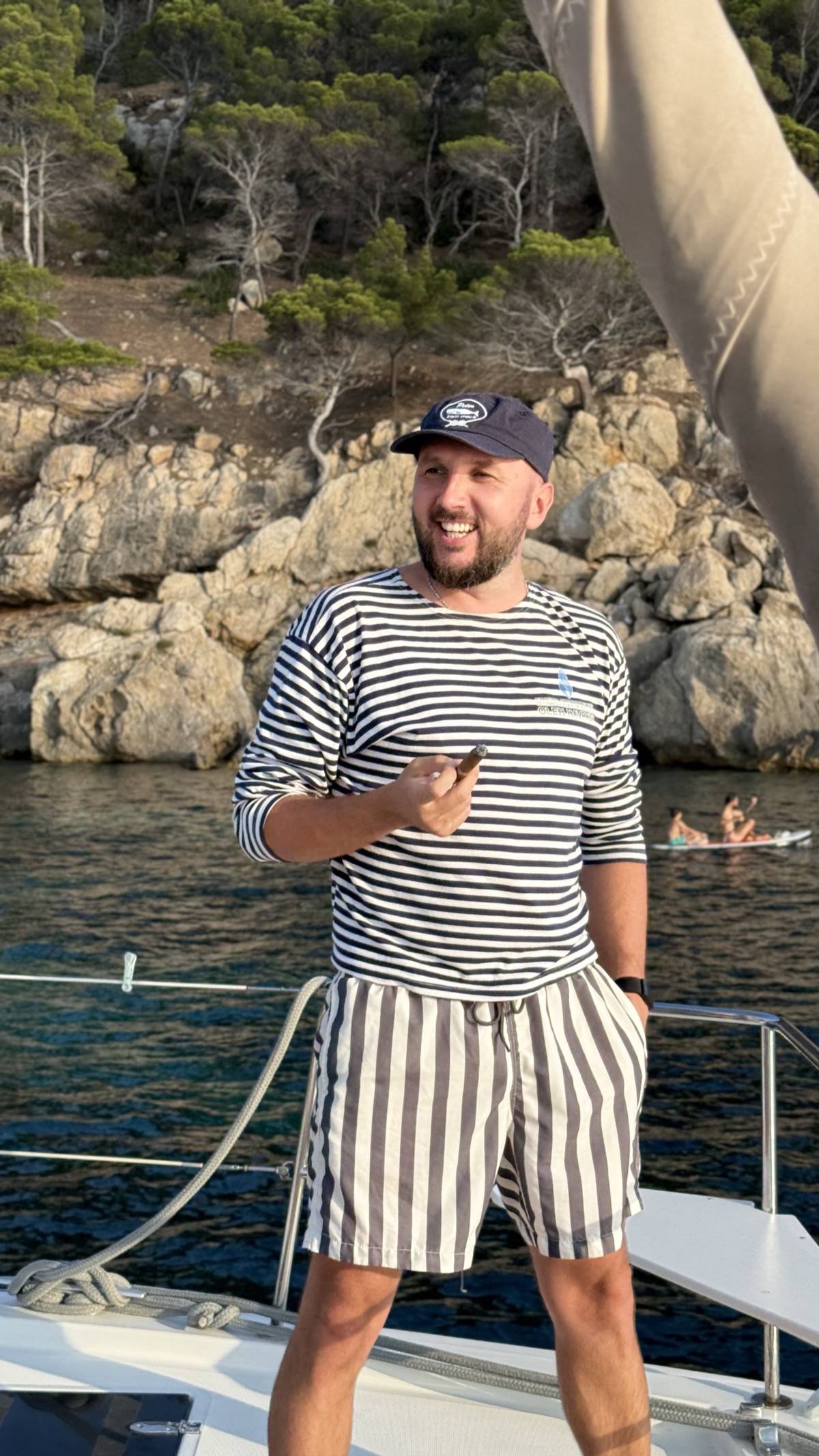 Roman laughing on the catamaran bow in striped shirt